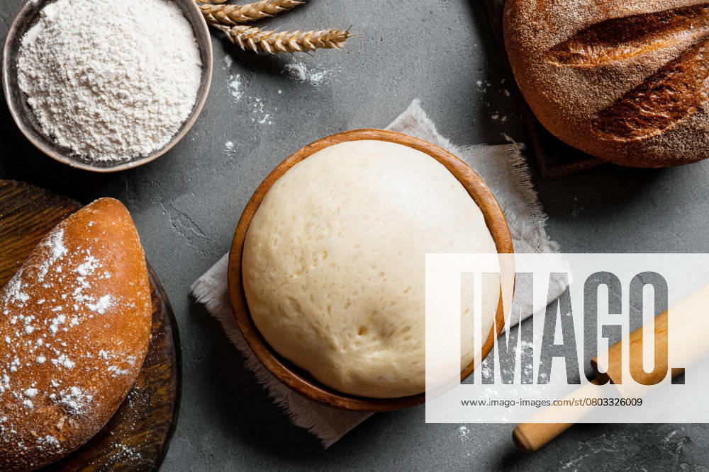 Schüssel mit frischem Teig, Backkonzept Bowl of fresh yeast dough with flour, rolling pin and fresh sourdough bread. Baking and kneading concept background.