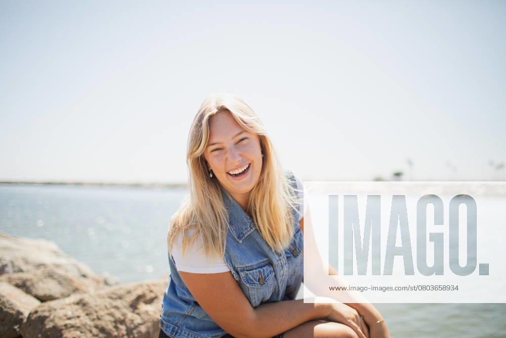 Young Woman sitting on a rock by the ocean Long Beach, California, United States R_KFPD250217-1648448-01 ,model released, Symbolfoto