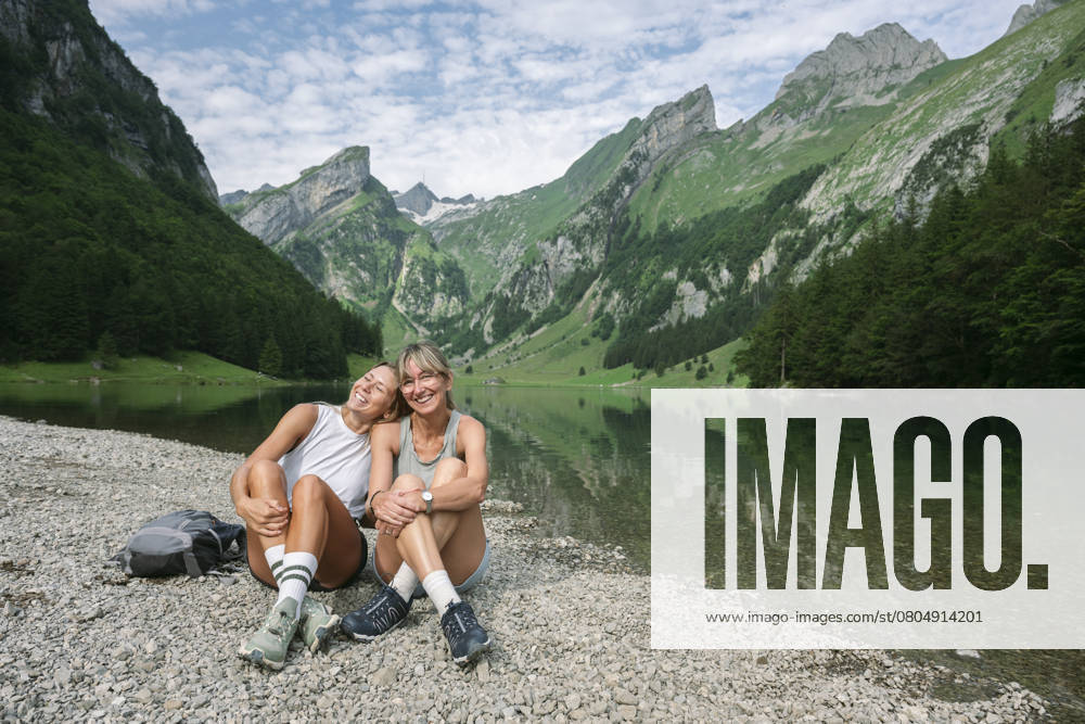 Smiling woman leaning on friend sitting near lake Seealpsee model released, Symbolfoto, FLMZF00469