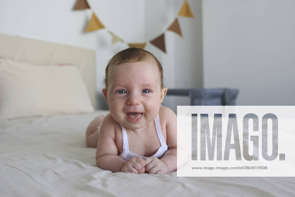 Happy baby girl lying on bed at home model released, Symbolfoto, SYEF00629