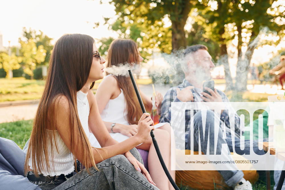 Sitting and smoking hookah. Group of young people have a party in the park at summer daytime., model released, , 51356588.jpg, group, people, hookah, smoking, culture, party, drink, cocktails, alcohol, sitting, relaxing, resting, beverage, armchair, bags, fun, together, outdoors, outside, summer, park, green, grass, caucasian, white, european, ethnicity, casual, clothes, wear, joy, cheerful, wellness, wellbeing, nice, positive, emotions, friends, weekend, leisure, free, time, sunlight, sunshine, beautiful, conversation, talking, communicating, socializing, young RECORD DATE NOT STATED