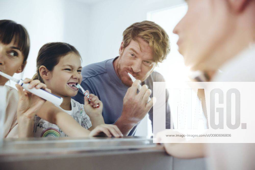 Family of three brushing their teeth in front of big mirror model released Symbolfoto property released MFF03694