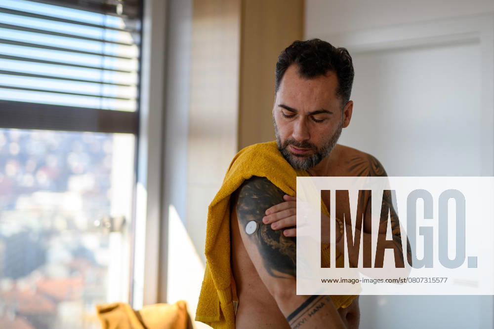 Diabetic man checking his CGM sensor after shower. Diabetic man checking his CGM sensor on arm after shower. model released