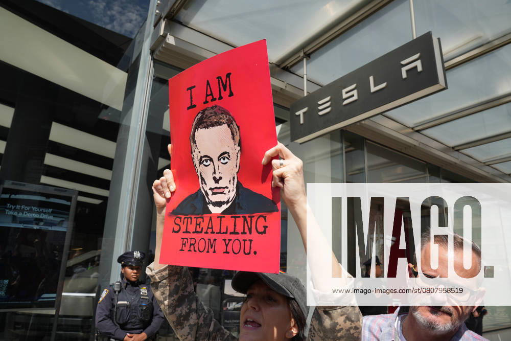Protesters with signs at the Tesla Takedown NYC + ACT UP 38th Anniversary Action: Death by 1000 Musk Cuts at the Tesla showroom in the Meatpacking District on March 29, 2025 in New York. New York USA - ZUMAb148 20250329_zap_b148_021