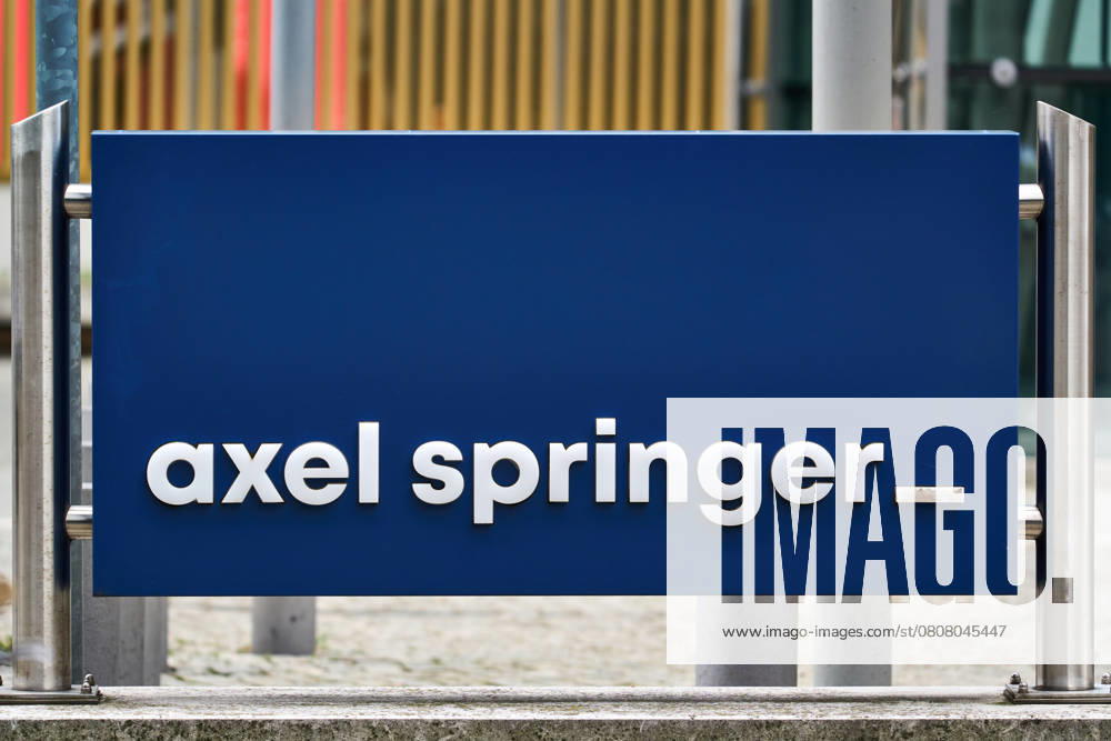 Blue sign with white axel springer lettering in front of the Axel Springer skyscraper in Berlin