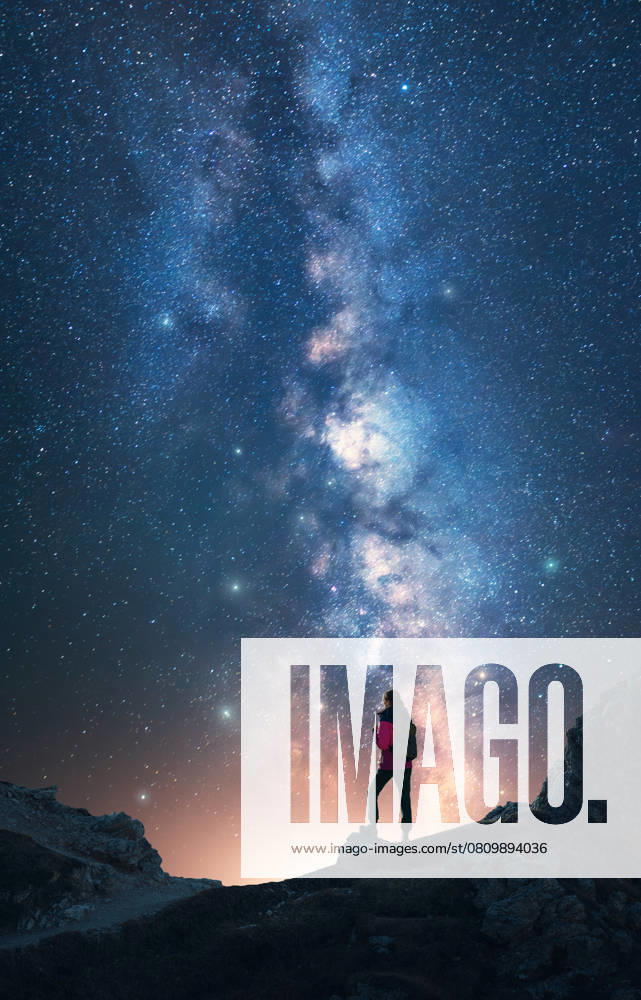 Glowing Milky Way and woman on mountain peak at starry night. Dolomites, Italy. Galaxy. Space landscape with silhouette of a girl, rocks, sky with bright stars. Milky Way and hiker. Vertical landscape Model Released DenisBilytskyi_ID27833_798980_006