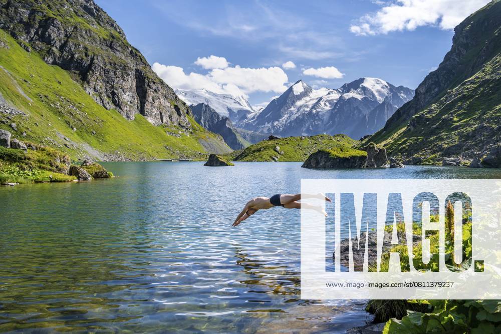 Mann macht Kopfsprung, Abkühlung beim Baden in Bergsee Lac de Louvie, hinten Gipfel der Grand Combin, Val de Bagnes, Wallis, Schweiz, Europa Man taking a header, cooling off while swimming in the mountain lake Lac de Louvie, behind the summit of the Grand Combin, Val de Bagnes, Valais, Switzerland, Europe
