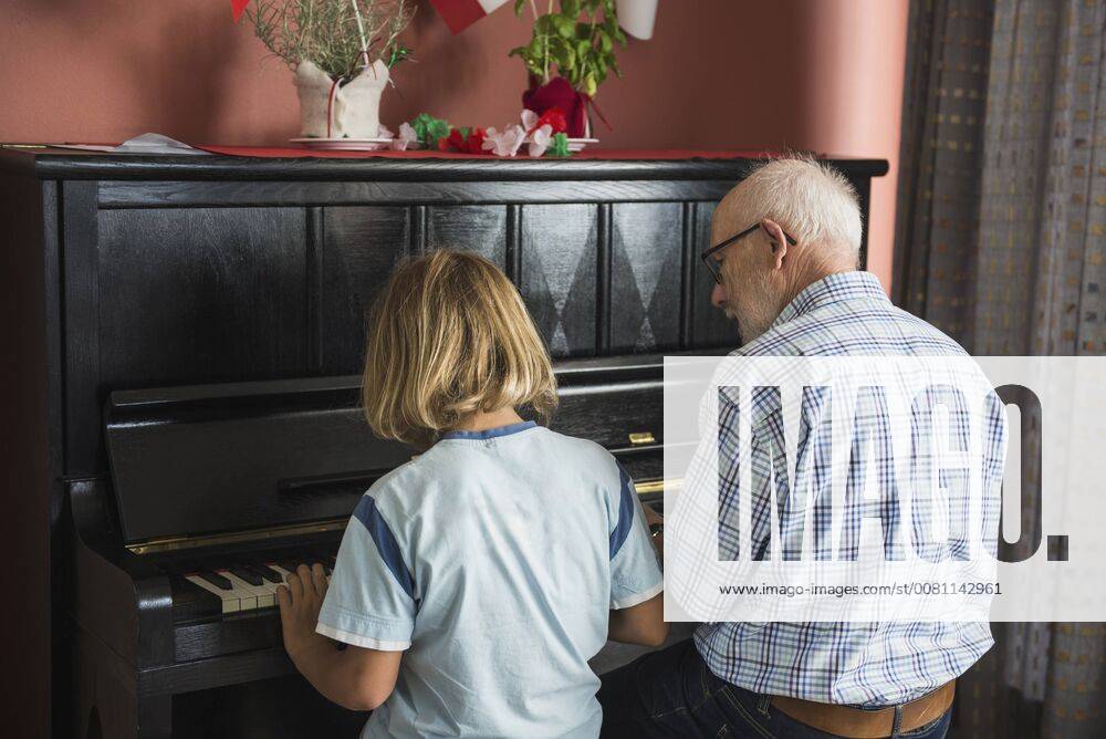 IMAGO Creative: Bildung, Musikerziehung Grandfather and grandson playing piano instrument, Eichenau, Bavaria, Germany mit_2017_10079