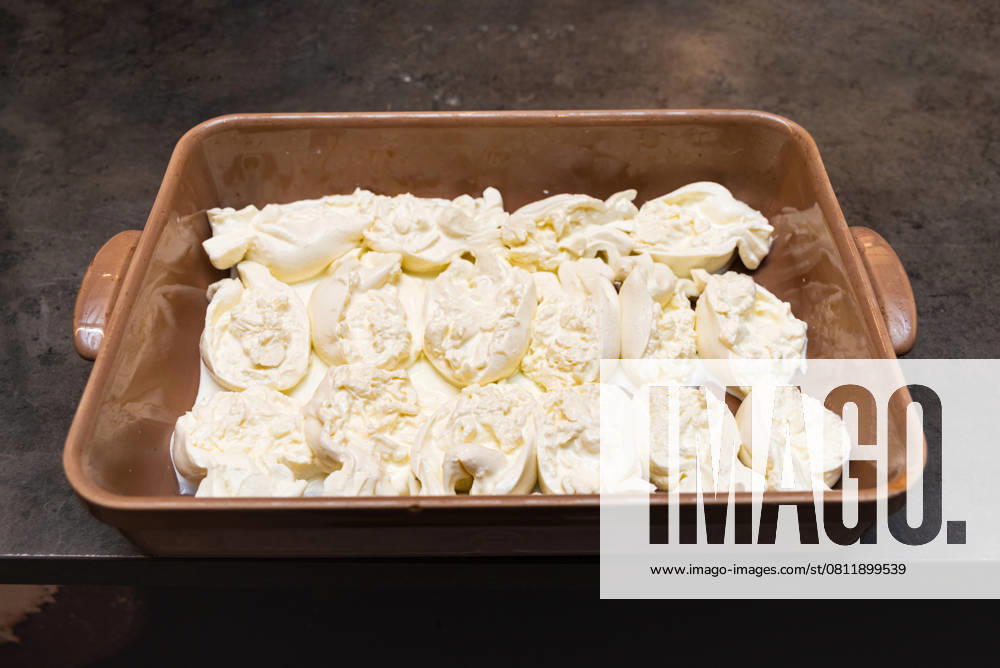 Burrata-Käsekugeln in einer Schale mit schwerer Sahne. Fresh burrata cheese balls served in a rich layer of heavy cream, displayed in a tray for catering or gourmet preparation. (License=RF)