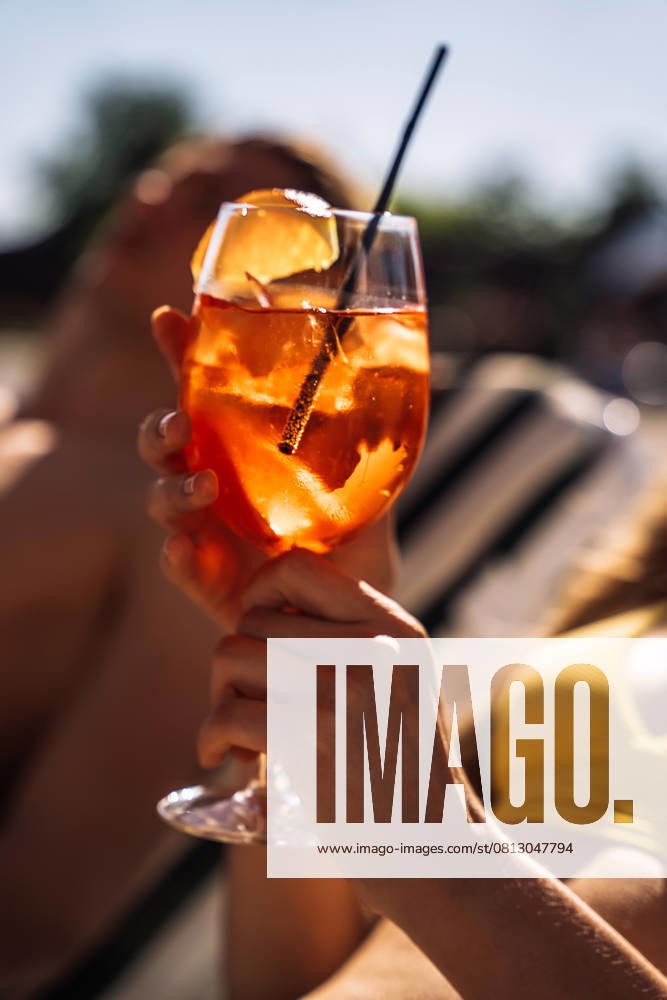Closeup of young womans hand with neat red manicure holds elegant glass with long stem of aperol. Tasty citrus cocktail with orange slice. Sunny day, spa resort. , 59224822.jpg, drink, aperol, woman, glass, female, resort, luxury, spa, lifestyle, cocktail, summer, sun, swimsuit, travel, relaxation, relax, vacation, pool, outdoors, water, adult, young, holiday, blue, happy, girl, people, orange, person, summertime, leisure, sunlight, sexy, model, beach, happiness, poolside, attractive, outdoor, body, beauty, portrait, sea, swimming, sunglasses, bikini, resting, caucasian, enjoyment, beautiful RECORD DATE NOT STATED