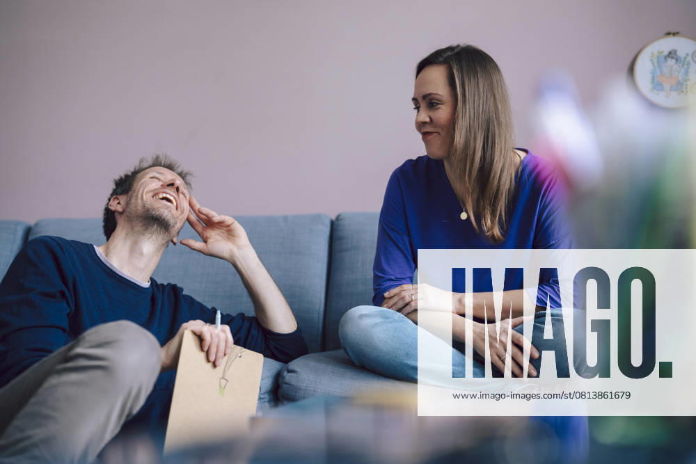 A couple enjoying a relaxed conversation at home on the sofa model released, Symbolfoto property released, KNSF11208