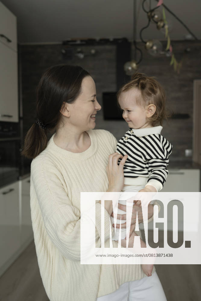 Mother holding her daughter in a cozy room smiling at each other model released, Symbolfoto property released, LESF00666