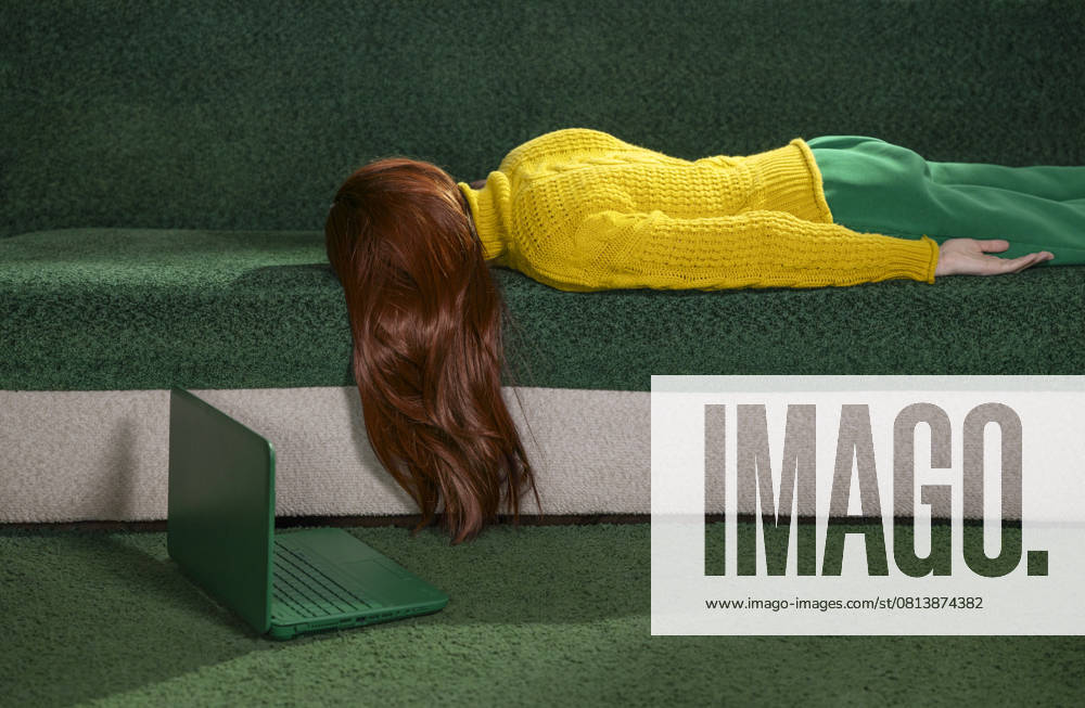 IMAGO Creative, Gesellschaft, Leisure Sickness Red-haired woman lying on a couch at home with a laptop, appearing tired and resting. model released, Symbolfoto, MBLF00807
