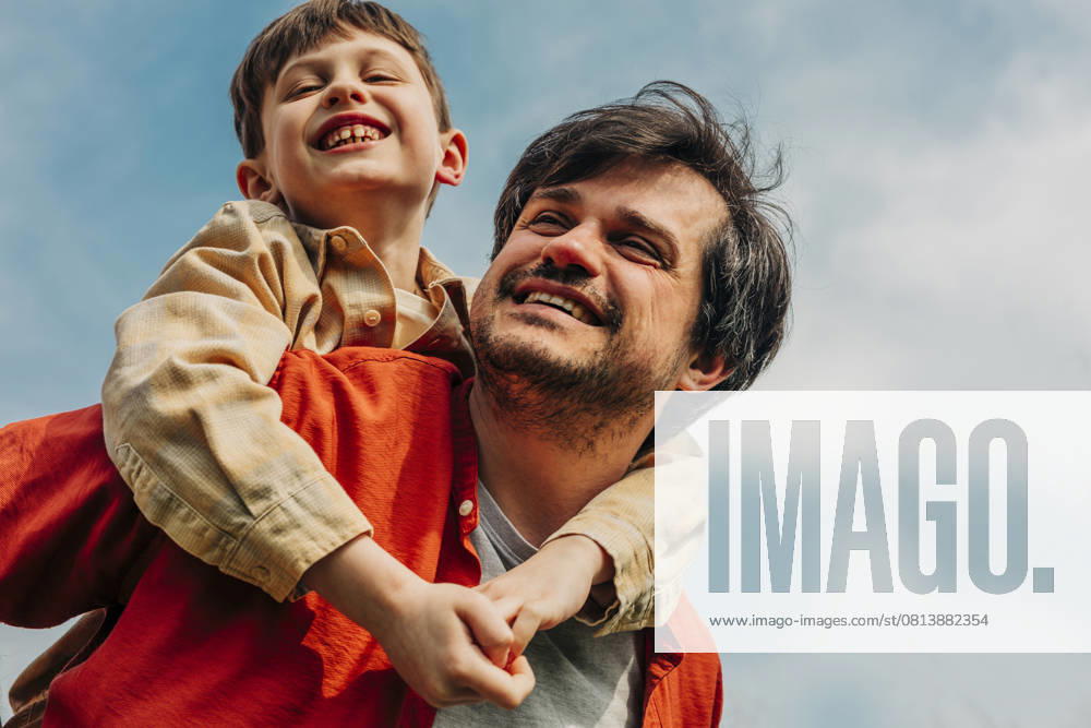 Father giving son a piggyback ride outdoors under a blue sky model released, Symbolfoto, VSNF03050