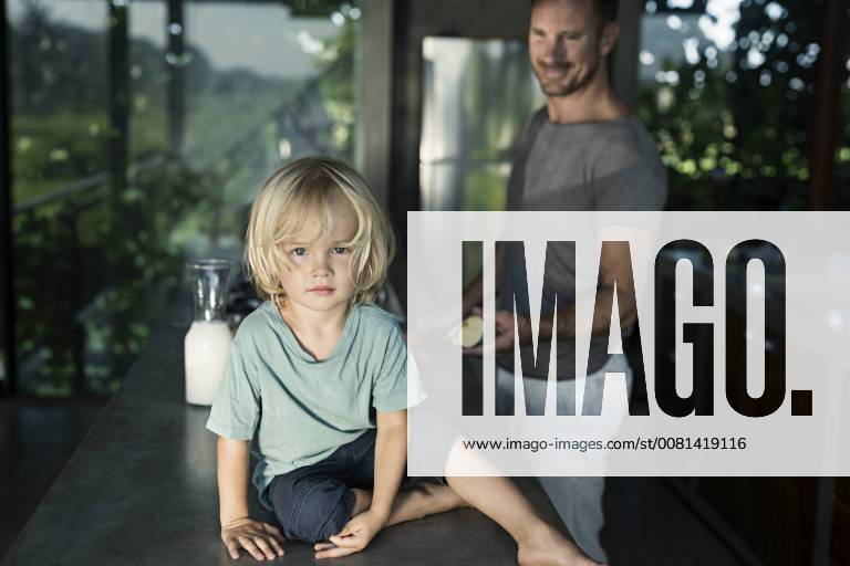 Son sitting on counter in kitchen while father is preparing breakfast model released Symbolfoto property released SBOF00887