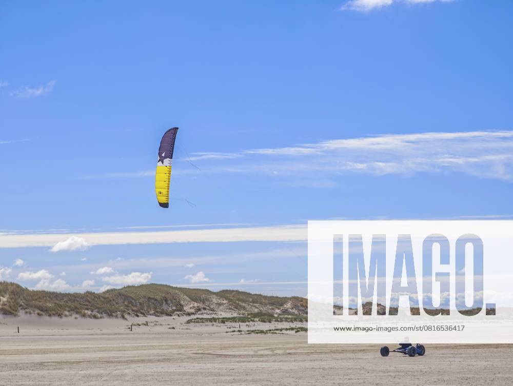 Freizeitsport Strandkiten am Rand des Nationalpark und UNESCO Weltnaturerbe, ausgewiesenes Kitegebiet, Kitebuggy mit beiden Füssen lenken, Fahrersitz mit Kiter zwischen Hinterachse und Vorderrad, hohe Geschwindigkeit, Westwinde, Dünen am Strand, Sonnenschein und blauer Himmel, Sankt Peter-Ording, Schleswig-Holstein, Deutschland, Europa Recreational sport Beach kiting on the edge of the national park and UNESCO World Heritage Site, designated kite area, kite buggy steered with both feet, driver s seat with kiter between rear axle and front wheel, high speed, westerly winds, dunes on the beach, sunshine and blue sky, Sankt Peter-Ording, Schleswig-Holstein, Germany, Europe