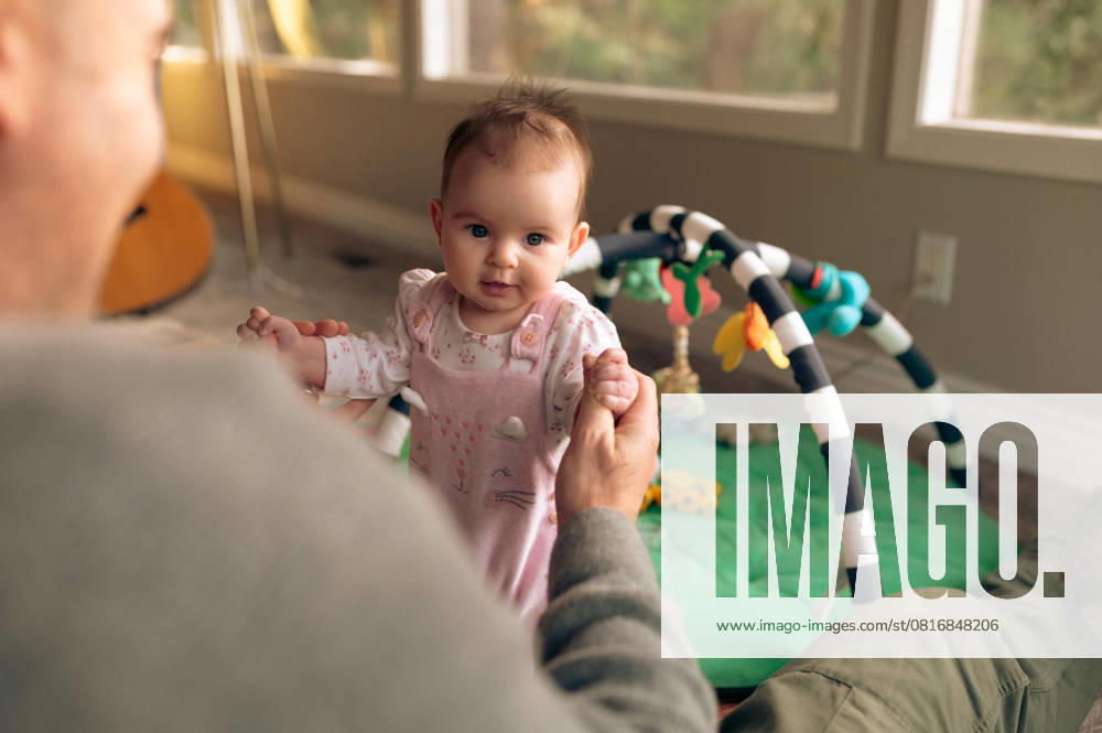 Baby balances with parent support in cozy living room Santa Cruz, California, United States CR_LICE250506-1720604-01 ,model released, Symbolfoto