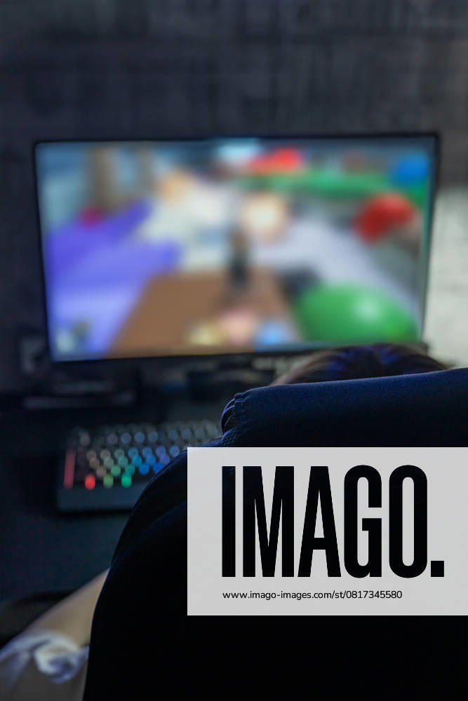 IMAGO Creative, Lifestyle, Gaming A focused teenage boy playing on a computer with a colorful keyboard and a large monitor displaying a game. The gaming setup creates an immersive experience Model Released Ikvyatkovskaya_ID28180_830143_013