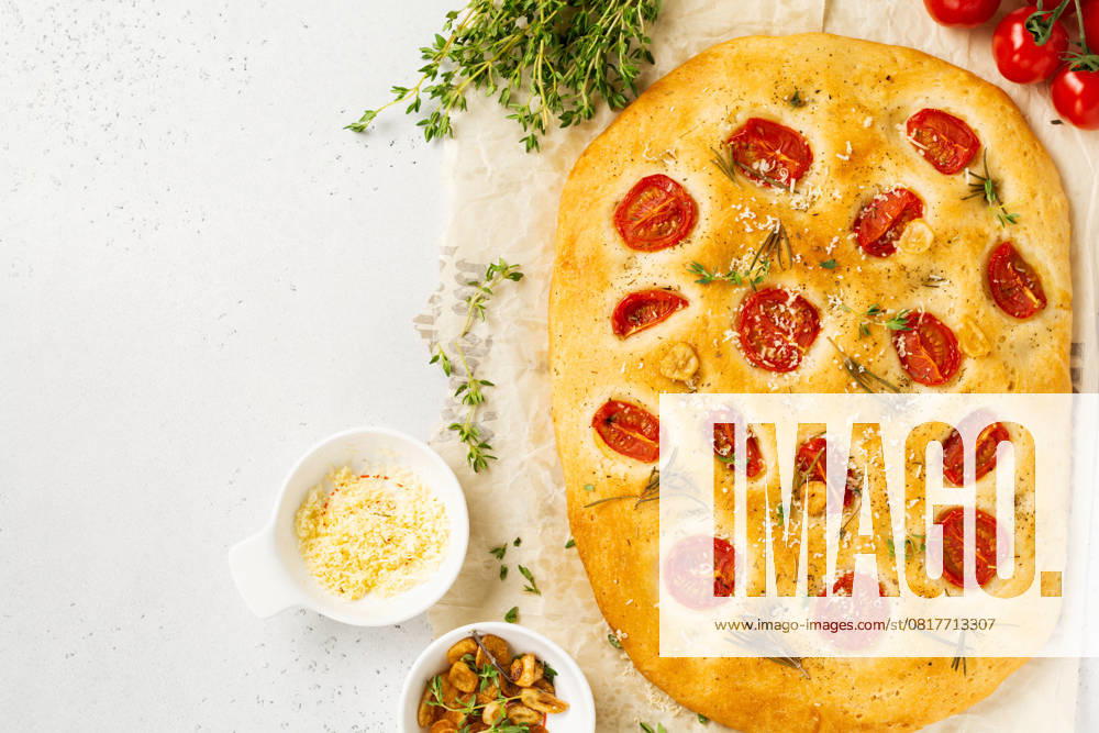 Hausgemachtes traditionelles italienisches Brot mit Kirschtomaten, Parmesan und Rosmarin auf rustikalem hellen Tischhintergrund. Ansicht von oben Hausgemachtes traditionelles italienisches Brot mit Kirschtomaten, Parmesan und Rosmarin auf rustikalem hellen Tischhintergrund. Ansicht von oben (License=RF)