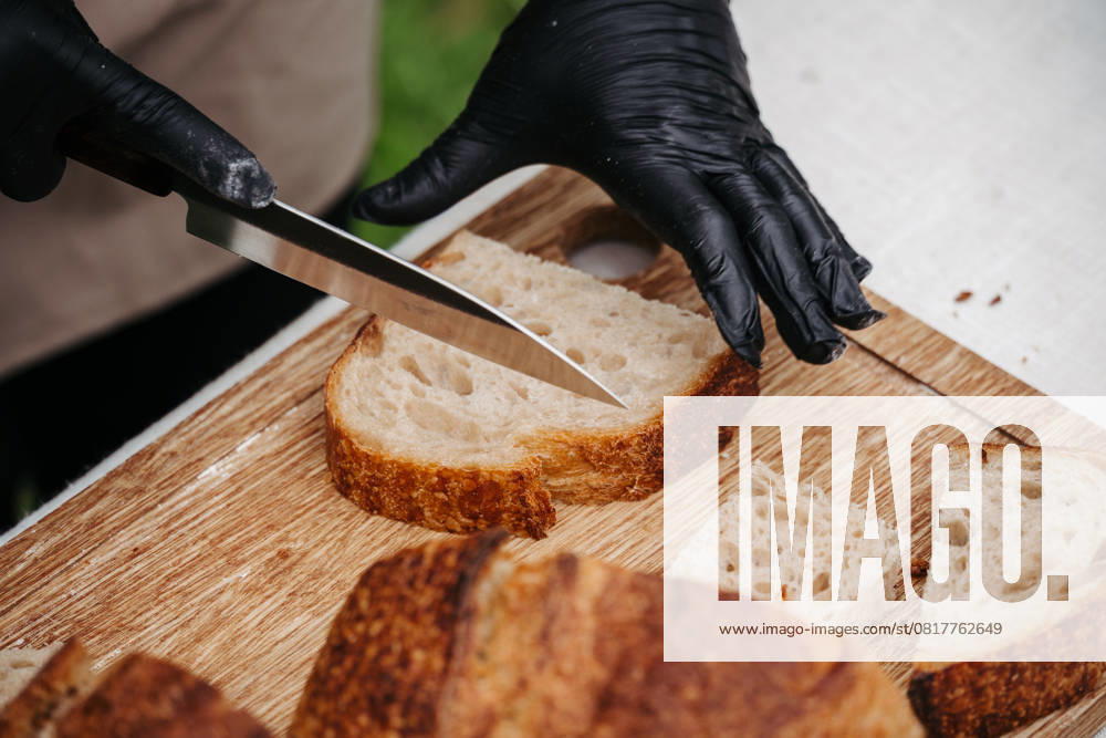 Cook cutting rustic sourdough bread on cutting board. Cook cutting resh rustic sourdough bread on wooden cutting board. model released
