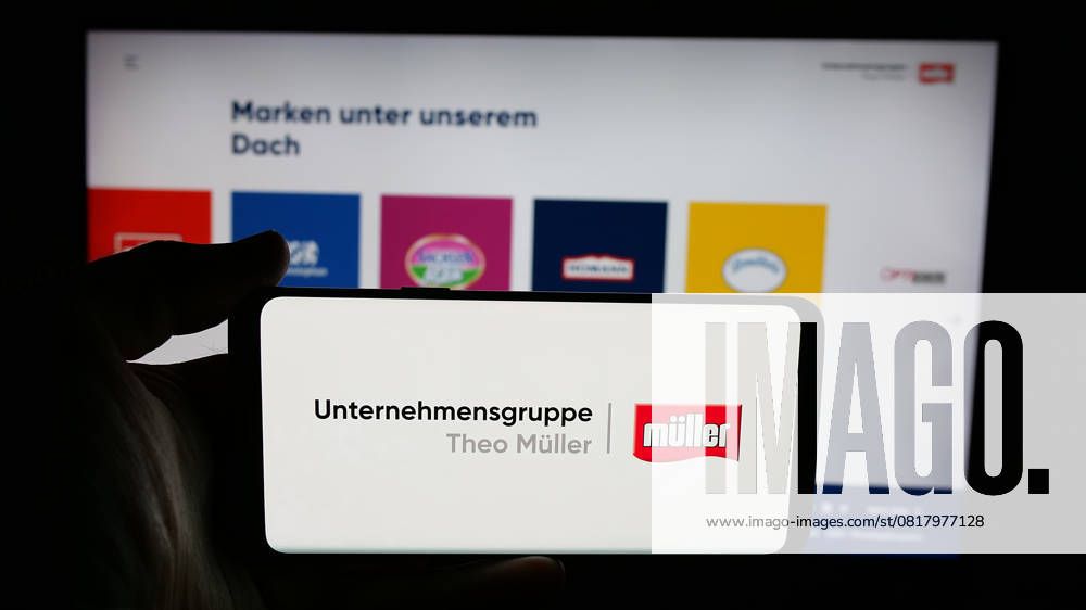 Illustration logos in Germany - 24 Apr 2025 In this photo illustration, a person is holding a cellphone with the logo of dairy company Unternehmensgruppe Theo Mueller on screen in front of webpage. Germany