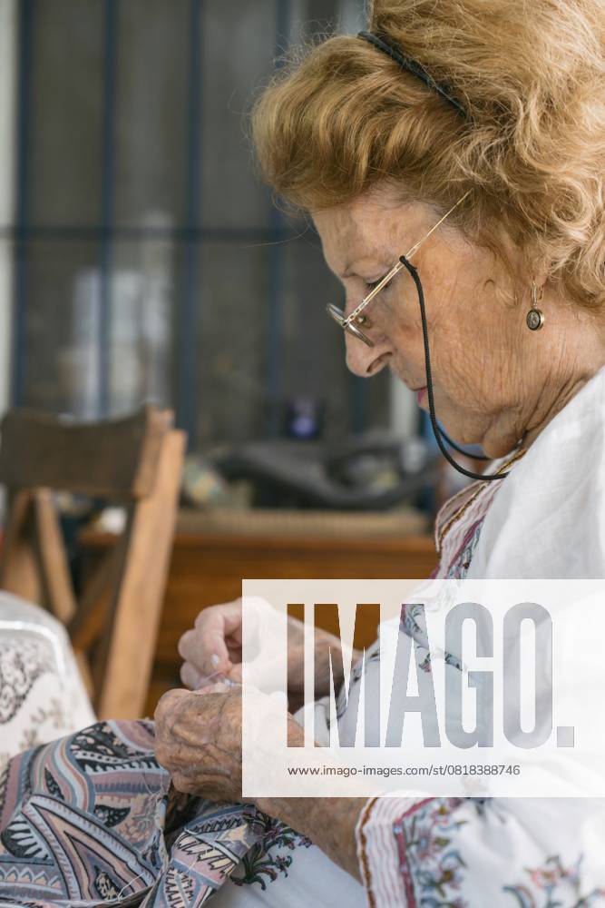 IMAGO Creative, Lifestyle, Freizeit, Hobby, Handarbeit, Nähen #2 Konzentrierte ältere Näherin, die mit Nadel und Faden akribisch Stoffe näht und dabei ihr Fachwissen und ihre Leidenschaft für das Schneidern in einer hellen, gemütlichen Umgebung unter Beweis stellt Focused elderly seamstress meticulously sewing fabric with needle and thread, demonstrating expertise and passion for dressmaking in a bright, cozy environment