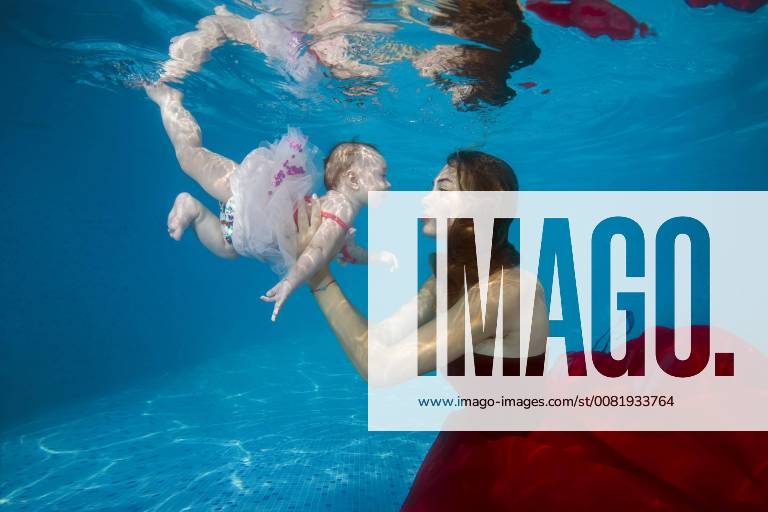 Beautiful young woman in a red dress with baby posing under water in the pool of Ukraine Europe