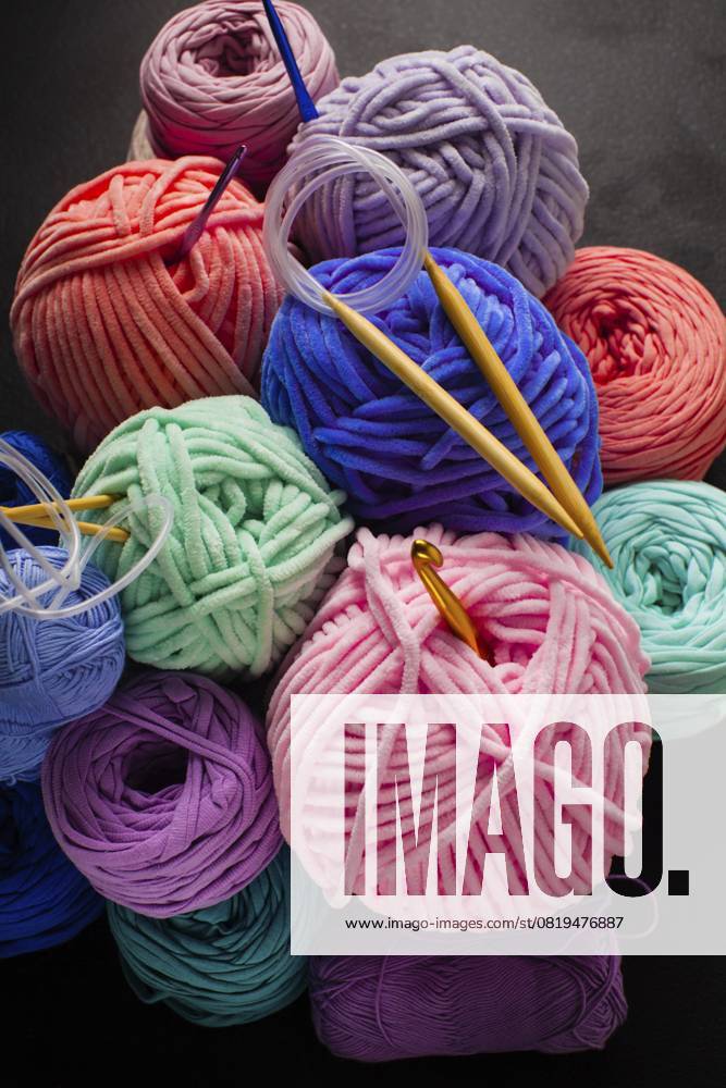 Haufen von Plüsch und Textilgarnkugeln mit Haken und Stricknadeln Heap of plush and textile yarn balls with hooks and knitting needles