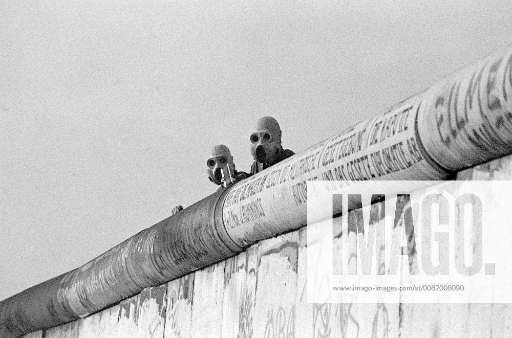 Berlin Wall June 1988 GDR border guards observe violent clashes between the West Berlin police and the autonomous squatters of the Lenné triangle at Potsdamer Platz on the wall with gas masks attached