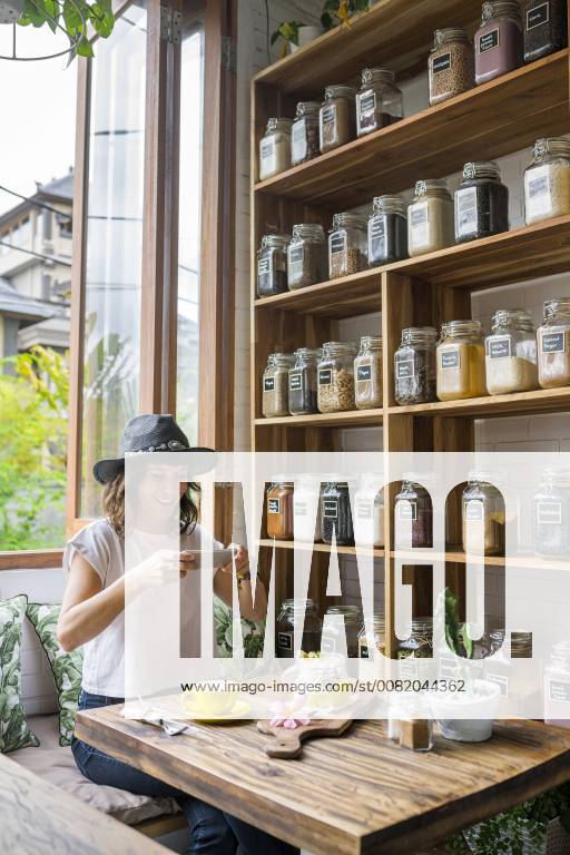 Woman with hat in a cafe taking picture of food with smartphone model released Symbolfoto property released SBOF01180