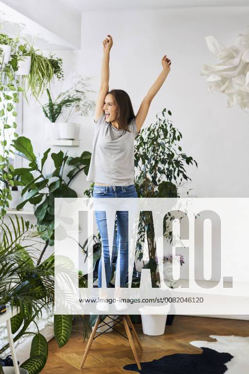 Young woman standing on chair in a room cheering model released Symbolfoto property released BSZF00161