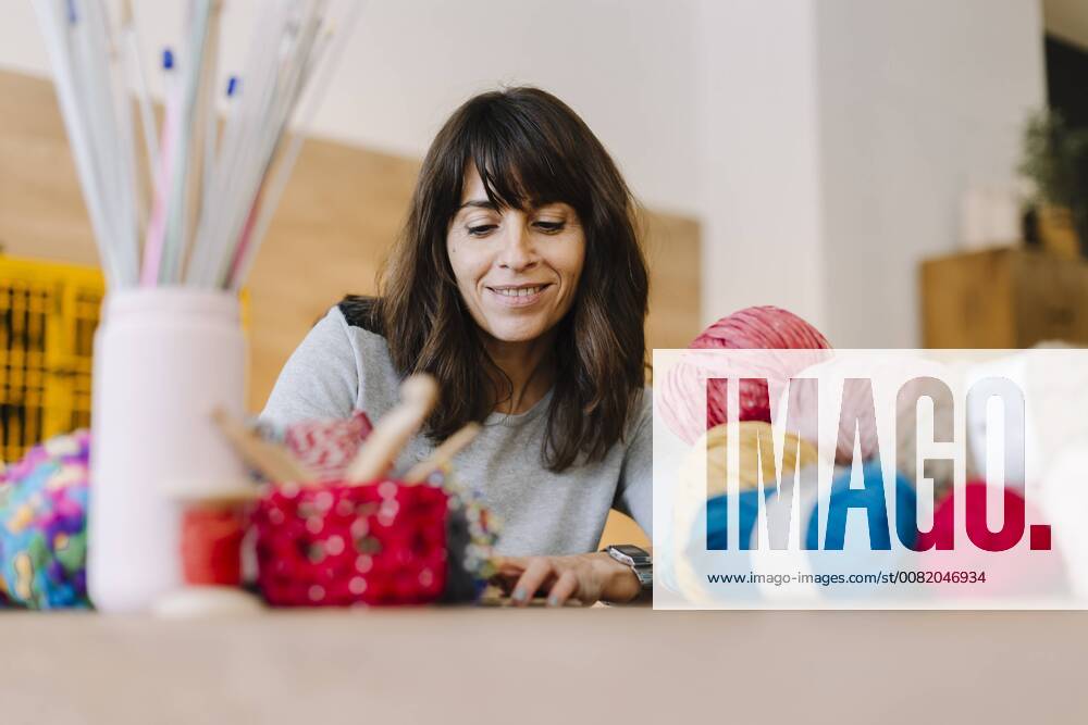 Smiling woman at table with knitting model released Symbolfoto property released OCAF00036