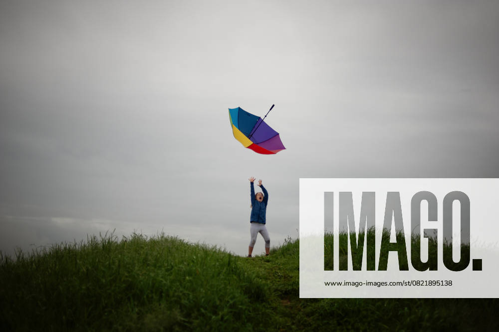 IMAGO Creative, Jahreszeit Sommer, Regen, Sommerregen Tween girl tossing colorful umbrella cloudy grey skies Ohio City, Ohio, United States CR_JOKU250606-1746366-01 ,model released, Symbolfoto