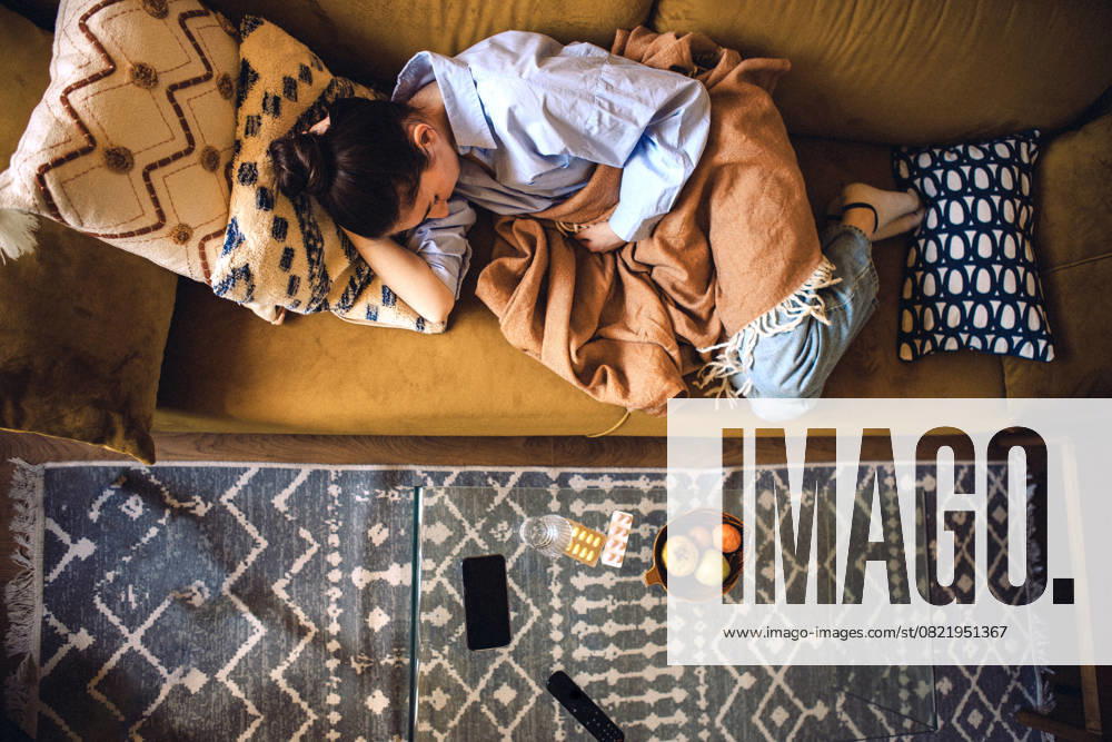 IMAGO Creative, Gesellschaft, Leisure Sickness Eine müde junge Frau liegt auf dem Sofa. Ein krankes Mädchen schläft auf der Couch zu Hause Eine müde junge Frau liegt auf dem Sofa. Ein krankes Mädchen schläft auf der Couch zu Hause (License=RF) ,model released, Symbolfoto