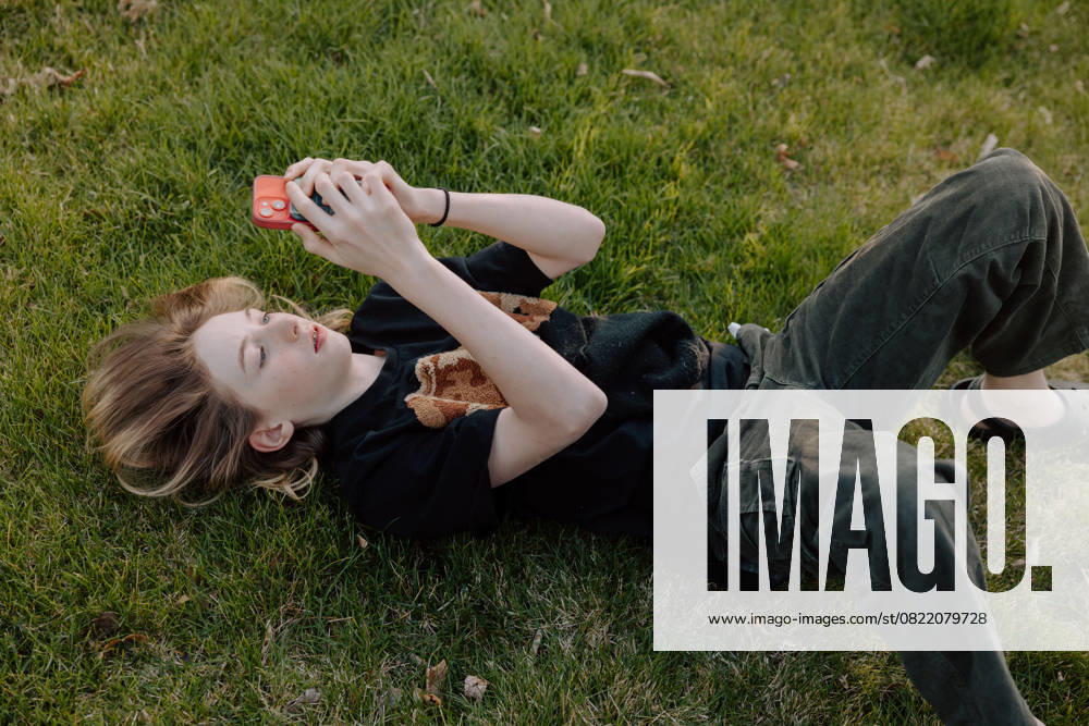 IMAGO Creative, Jahreszeit Sommer, Sommerferien Teenager boy lying on grass using smartphone outdoors Boise, Idaho, United States CR_PHZD250609A-1747604-01 ,model released, Symbolfoto