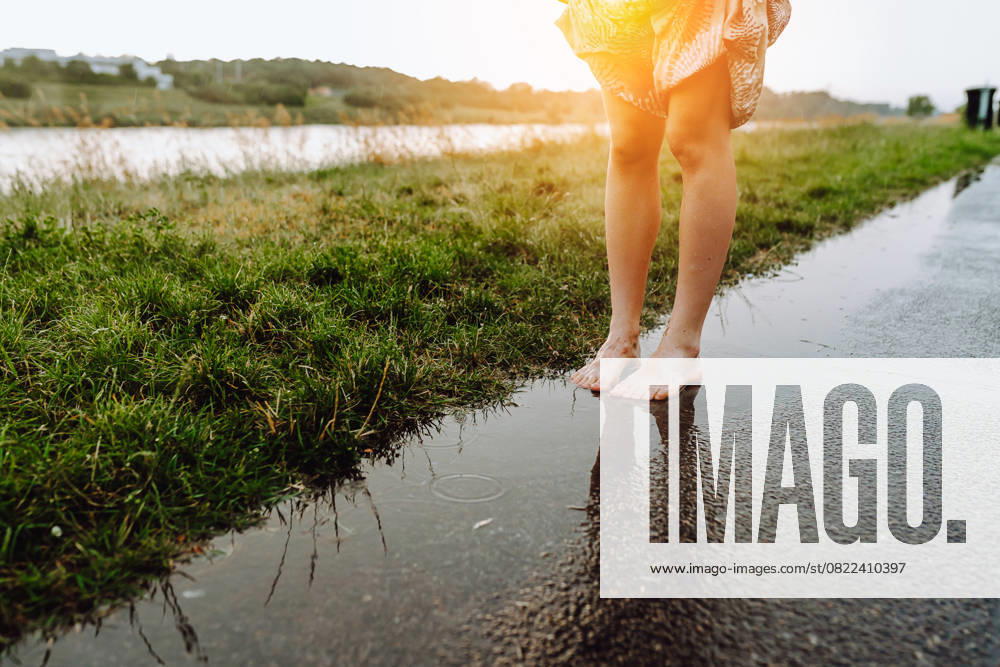 IMAGO Creative, Jahreszeit Sommer, Regen, Sommerregen Porträt Happy Tanzen barfuß in Pfützen, Teenager-Mädchen, mit nassen Haaren, in lockerer Sommerkleidung, bei Sonnenuntergang, nach dem Regen, in der Nähe von Fluss. Konzept der Natur genießen, Sonnenuntergang, Freiheit, Portrait Happy dancing barefoot in puddles, teenager girl, with wet hair, in loose summer clothes, at sunset, after rain, near river. concept of enjoying nature, sunset, freedom, (License=RF) ,model released, Symbolfoto