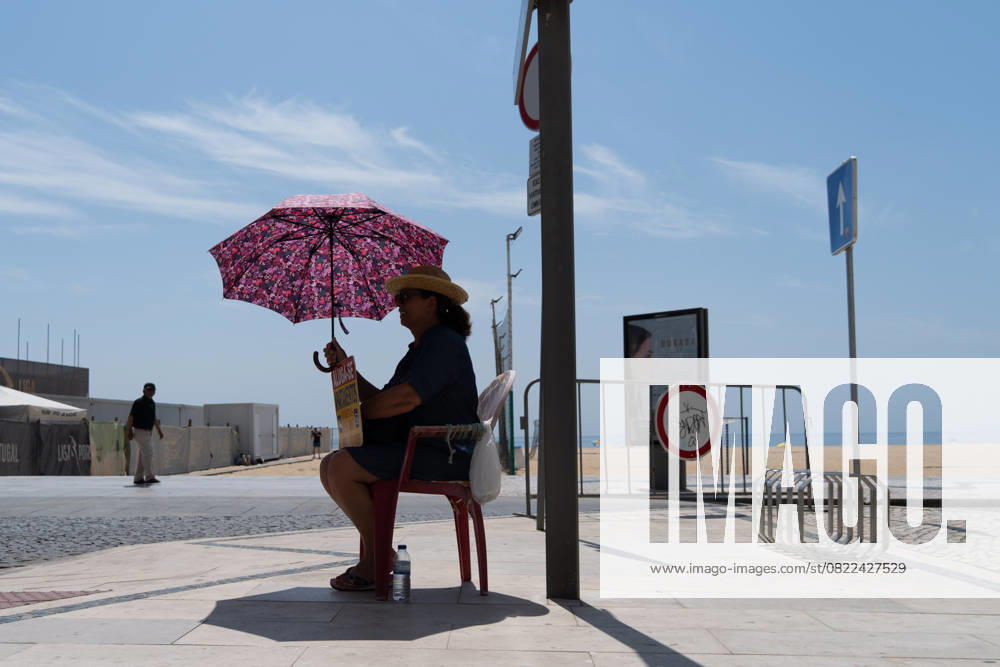 IMAGO Creative, Jahreszeit Sommer, Hitze June 17, 2025, Nazare, Santiago, Portugal: A woman shields herself from the sun with an umbrella on a hot day in Nazare, Portugal. Nazare Portugal - ZUMAb332 20250617_zip_b332_001