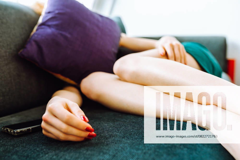 IMAGO Creative, Gesellschaft, Leisure Sickness junge rothaarige Frau liegt müde auf dem Sofa young woman lying on sofa covering head with pillow, stressed (License=RF) ,model released, Symbolfoto