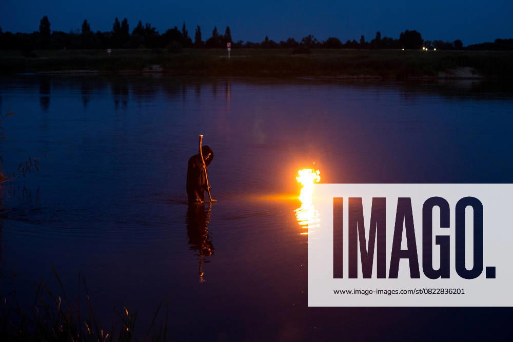 A man in black robe is standing in the Odra River during the Kupala Night celebrations. Kupala Night (Polish: Noc Kupa³y) is an old Slavic holiday celebrated on the night of the summer solstice. It combines the cult of nature, fertility, fire and water. Cigacice Poland - ZUMAs197 20250621_aaa_s197_469