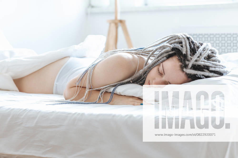 Young woman with dreadlocks sleeping in white bed. Saint Petersburg, Saint Petersburg, Russia CR_KSLI250620A-1729369-01 ,model released, Symbolfoto ,property released
