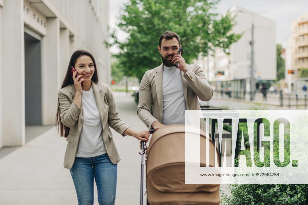 Mother and father with child in stroller talking on mobile phones while walking in the city model released, Symbolfoto, VSNF03424