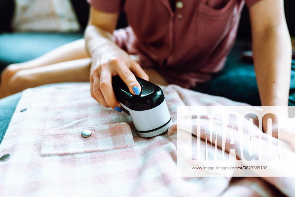 Frau pflegt Kleidung zu Hause, schneidet Flusen mit Werkzeug ab woman takes care of clothes at home, cuts off lint with tool, durable use of things, environmentally friendly (License=RF) ,model released, Symbolfoto
