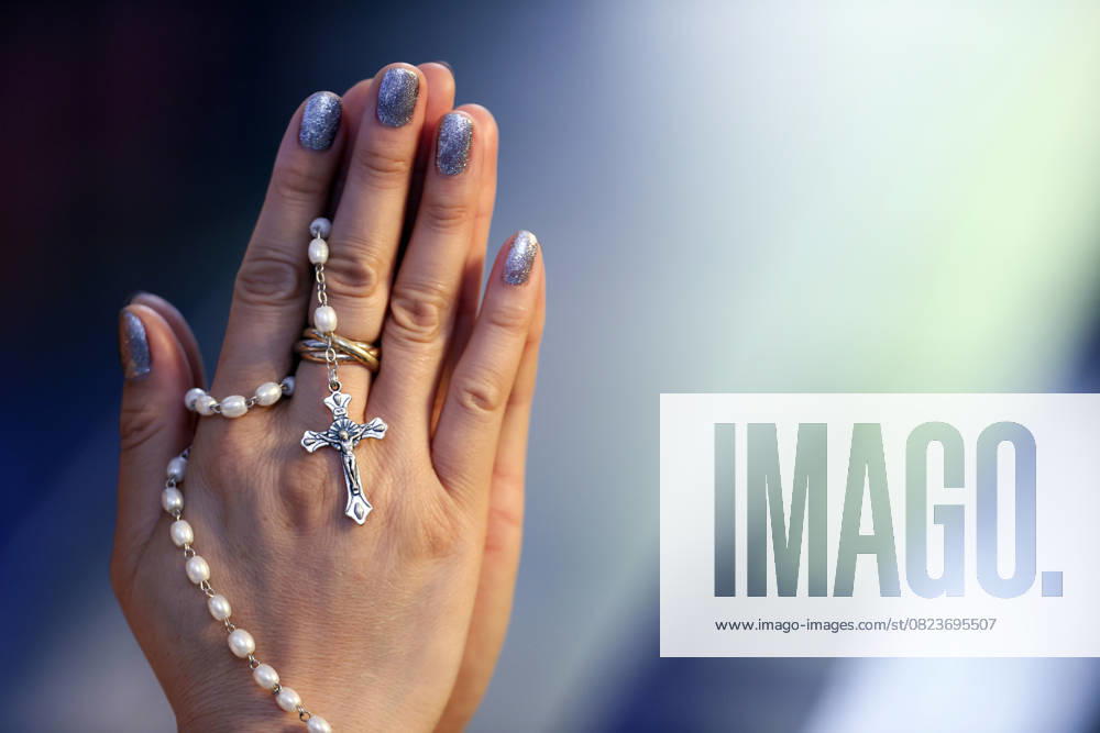 Catholic woman praying the Rosary in a church. Close up on hands and crucifix; Ho Chi Minh City Vietnam