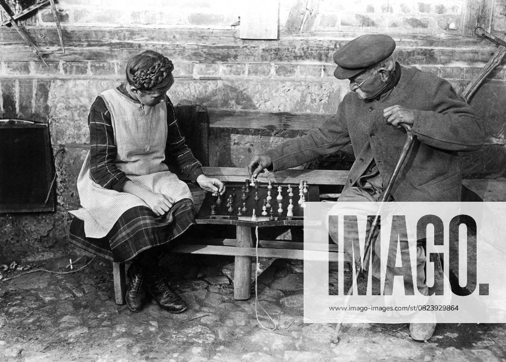 Alter Mann spielt Schach mit Mädchen 1900, Zwei ältere Personen spielen Schach auf einer Bank im Freien, Historisches Foto Old man playing chess with girl 1900, Two elderly people playing chess on a bench outdoors, Historical photo