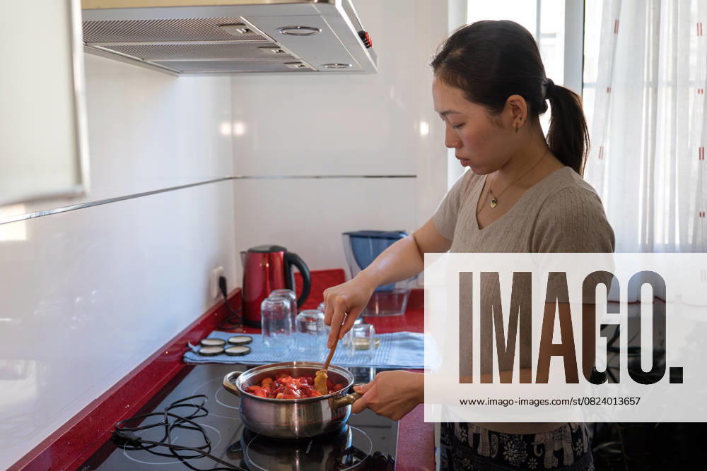 IMAGO Creative, Jahreszeit Sommer, Food, Marmelade kochen Young woman crafting homemade strawberry jam in kitchen A young Asian woman skillfully prepares homemade strawberry jam in a cozy kitchen setting, embodying a sustainable lifestyle, conscious consumption, and artisan food crafting Model Released JuanAlbertoRuiz_ID29313_965696_010