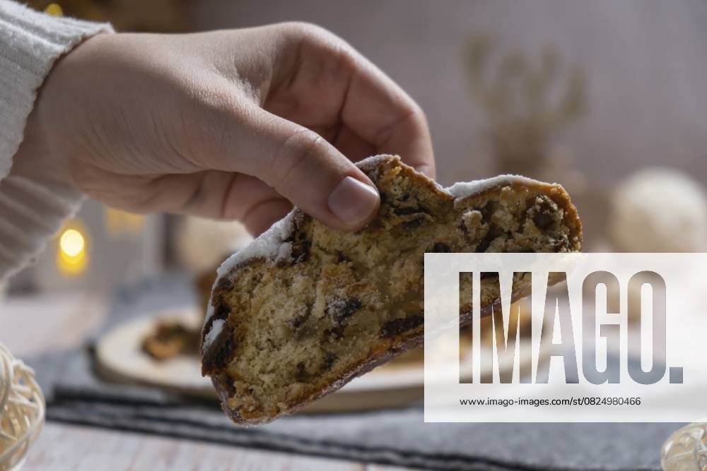 Weibliche Hand, die ein Stück von hausgemachten Weihnachten traditionellen Kuchen Kuchen mit Marzipan Nüsse und getrocknete Früchte Gebäck Dessert Stollen. Winterferien Saison Atmosphäre. Leckere leckere Zusammensetzung nach Hause Tisch Einstellung Textfreiraum Female hand taking slice of Homemade Christmas traditional cake pie with marzipan nuts and dried fruits pastry dessert stollen. Winter holidays season atmosphere. Delicious tasty composition home table setting Copy space