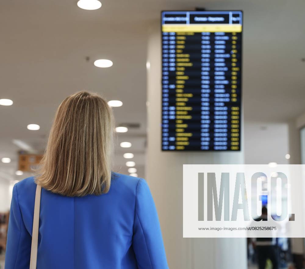 Frau im Geschäftsanzug bei der Kontrolle ihres Fluges im Flughafen Woman in business suit in checking her flight in airport