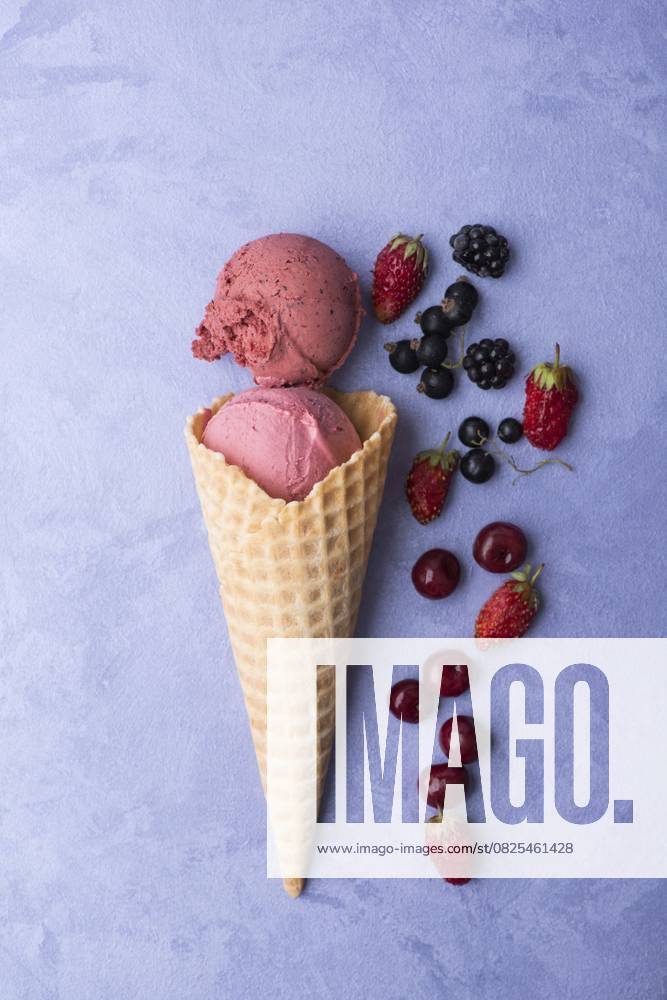 Eis mit Beeren in einem Waffelhorn auf ornamentalem lila Hintergrund, Ansicht von oben Ice cream with berries in a waffle horn on an ornamental purple background, top view