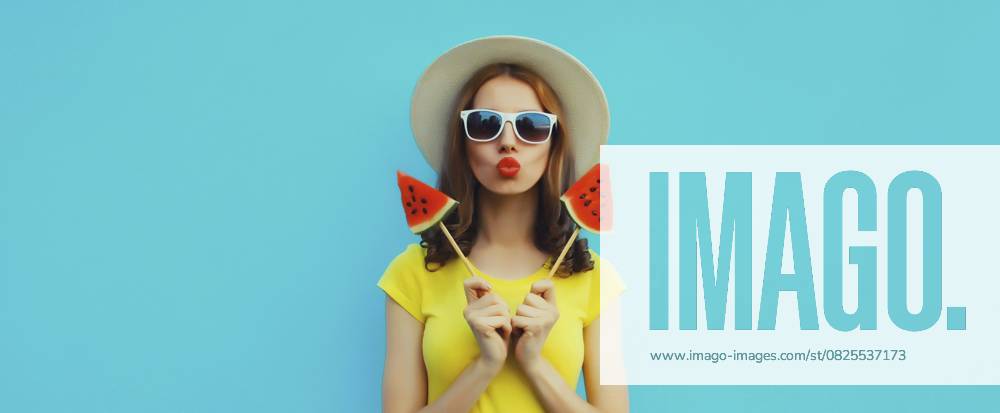 Sommer Porträt der stilvollen jungen Frau mit süßen saftigen Lutscher oder Eis geformt Scheibe Wassermelone trägt Strohhut auf blauen Studio Hintergrund Summer portrait of stylish young woman with sweet juicy lollipop or ice cream shaped slice of watermelon wearing straw hat on blue studio background