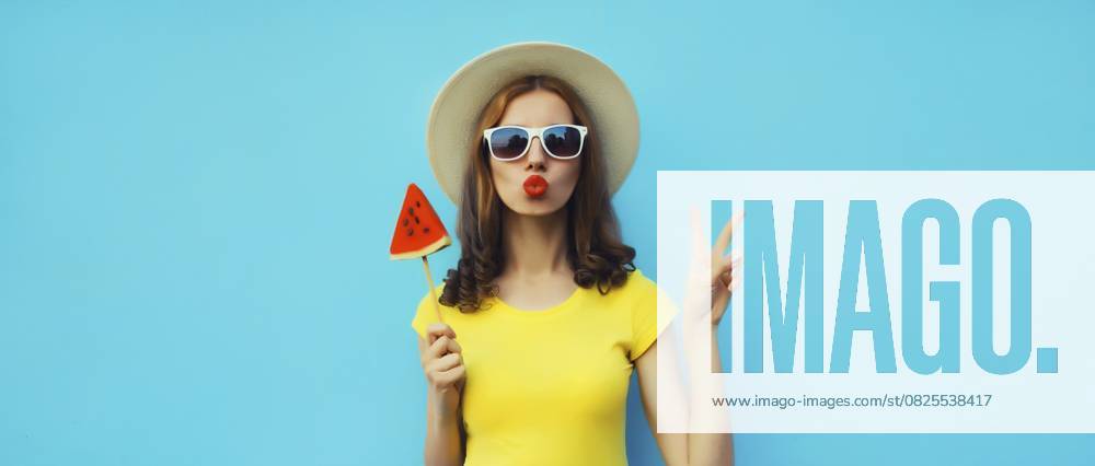 Sommer Porträt der stilvollen jungen Frau mit süßen saftigen Lutscher oder Eis geformt Scheibe Wassermelone trägt Strohhut auf blauen Studio Hintergrund Summer portrait of stylish young woman with sweet juicy lollipop or ice cream shaped slice of watermelon wearing straw hat on blue studio background